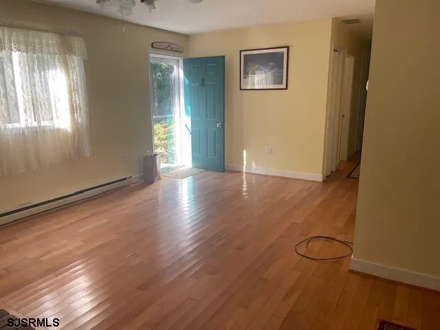 a view of an empty room with wooden floor and a window