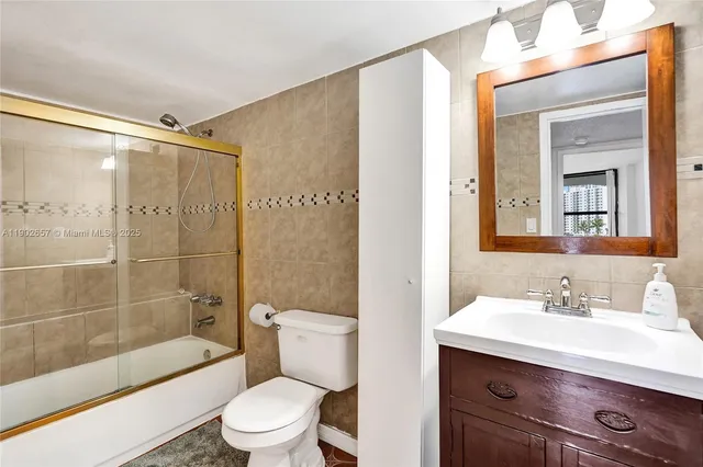 a bathroom with a sink a toilet a mirror and a glass door shower