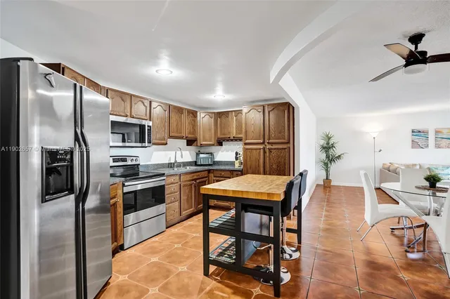 a kitchen with stainless steel appliances granite countertop a refrigerator a stove a sink a dining table and chairs with wooden floor