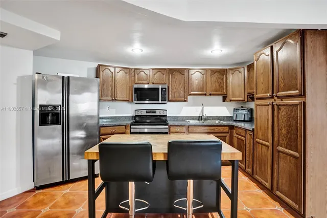 a kitchen with stainless steel appliances granite countertop a refrigerator a stove a sink a microwave and a refrigerator