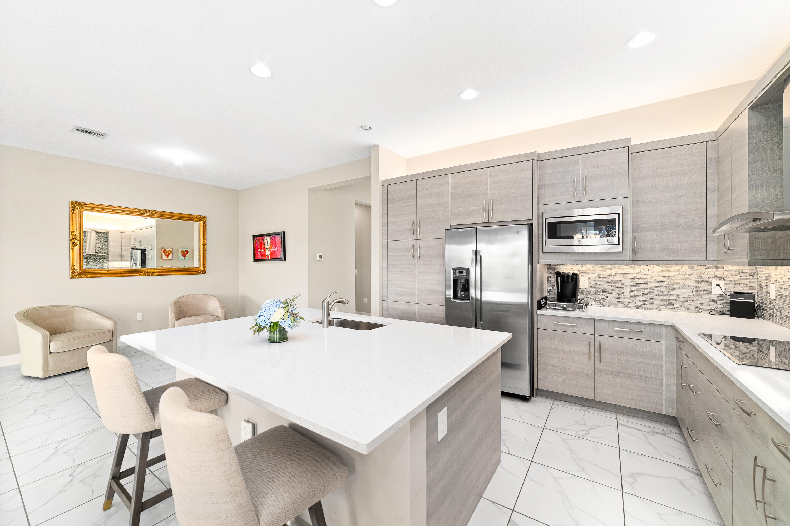15380 Blue River Road Delray Beach, FL 33446 - Photo 8 of 31 a large kitchen with white cabinets a sink dishwasher a dining table and chairs
