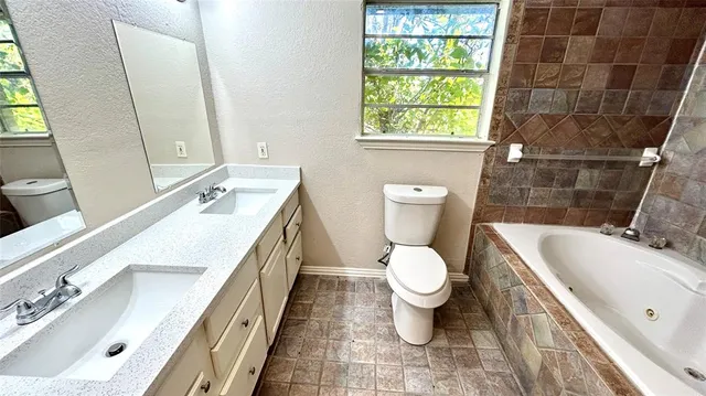 a bathroom with a double vanity sink toilet and a bathtub