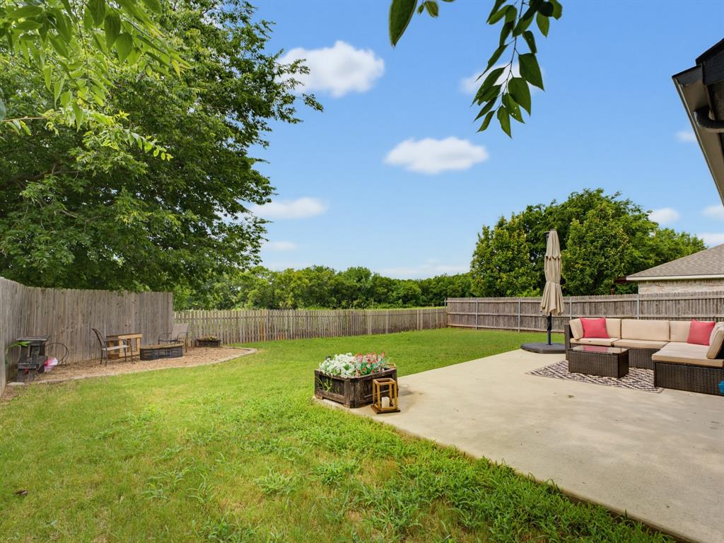 600 Stirling Road Rhome, TX 76078 - Photo 29 of 38 Expansive backyard featuring a concrete patio, wood privacy fencing, and lush green lawn