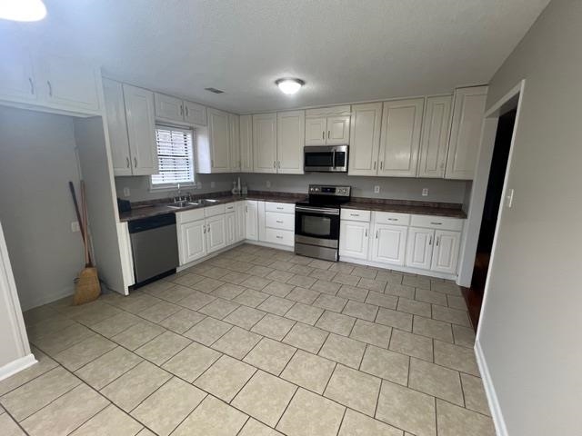 2541 Ray Bluff Road Millington, TN 38053 - Photo 7 of 12 Kitchen featuring dark countertops, appliances with stainless steel finishes, white cabinetry, and light tile patterned flooring