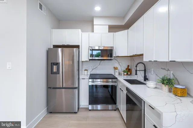 a kitchen with stainless steel appliances a refrigerator a sink a stove a microwave and cabinets