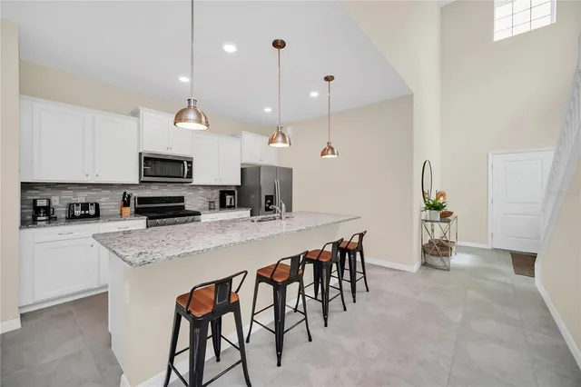 a kitchen with stainless steel appliances kitchen island granite countertop a table chairs sink and cabinets