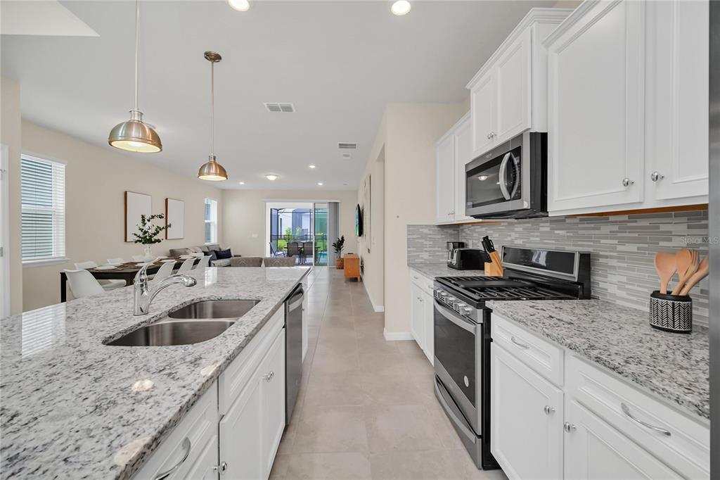 7196 Oakmoss Loop Davenport, FL 33837 - Photo 12 of 48 a kitchen with stainless steel appliances granite countertop a sink a stove and a wooden floors