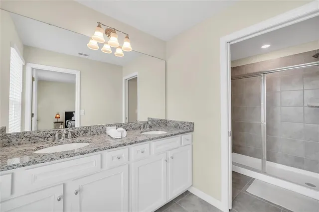 a bathroom with a granite countertop sink a large mirror and a shower