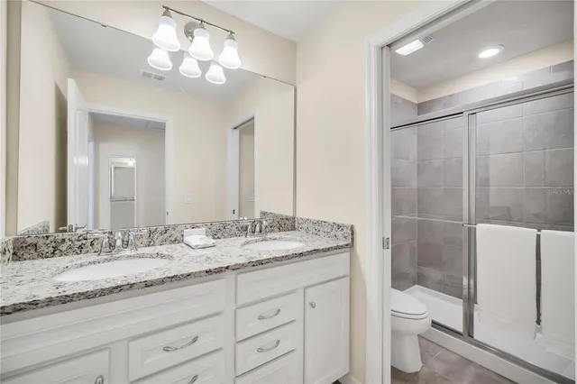 a bathroom with a granite countertop sink a toilet and a large mirror