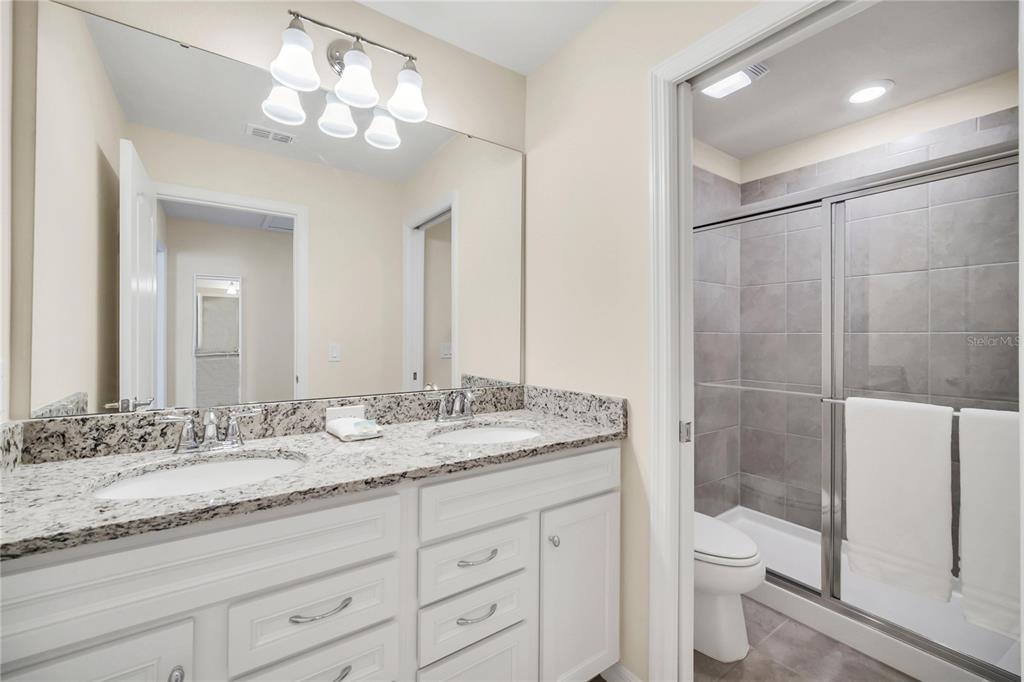 7196 Oakmoss Loop Davenport, FL 33837 - Photo 23 of 48 a bathroom with a granite countertop sink a toilet and a large mirror