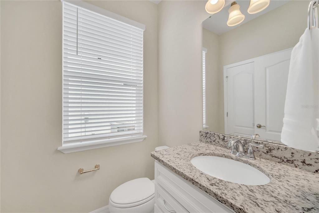 7196 Oakmoss Loop Davenport, FL 33837 - Photo 32 of 48 a bathroom with a granite countertop sink toilet a mirror and a window