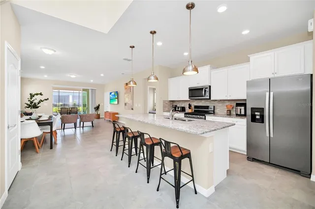 a large kitchen with kitchen island a dining table chairs and a wooden floor