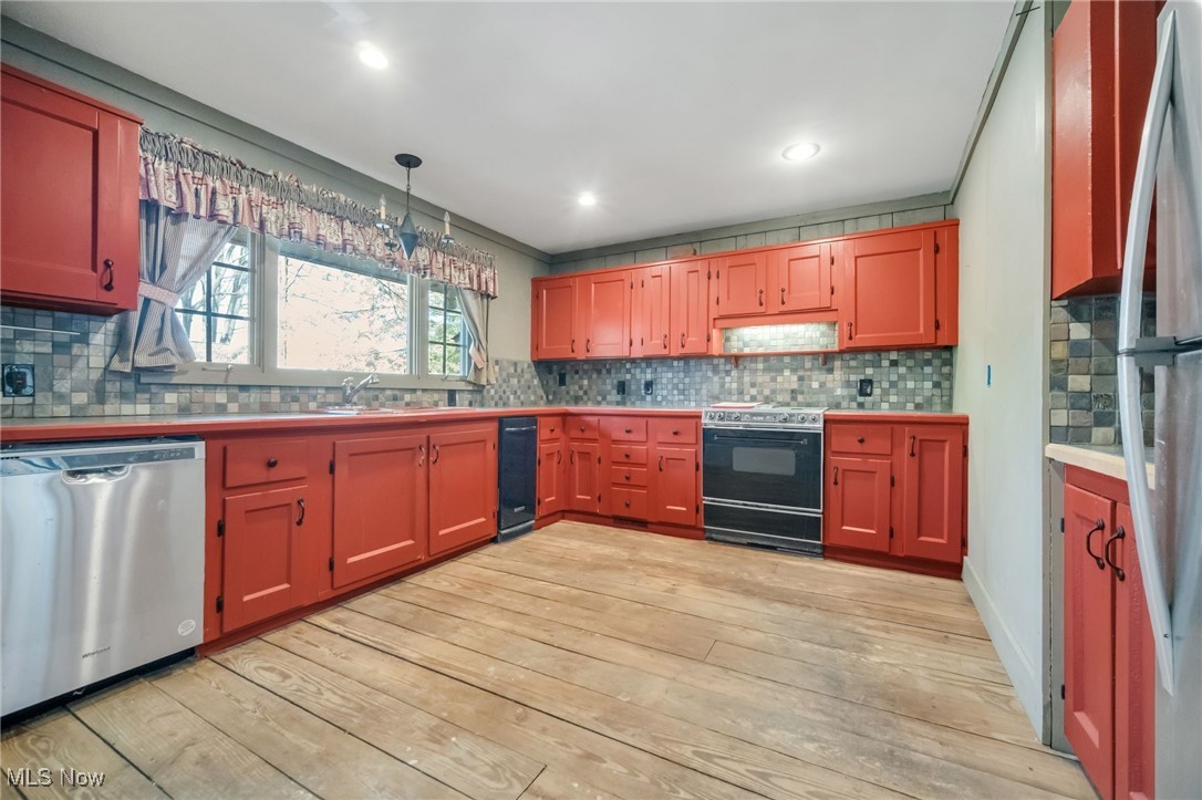 18060 Falling Leaves Road Strongsville, OH 44136 - Photo 10 of 43 Kitchen with hanging light fixtures, appliances with stainless steel finishes, light wood-type flooring, and tasteful backsplash