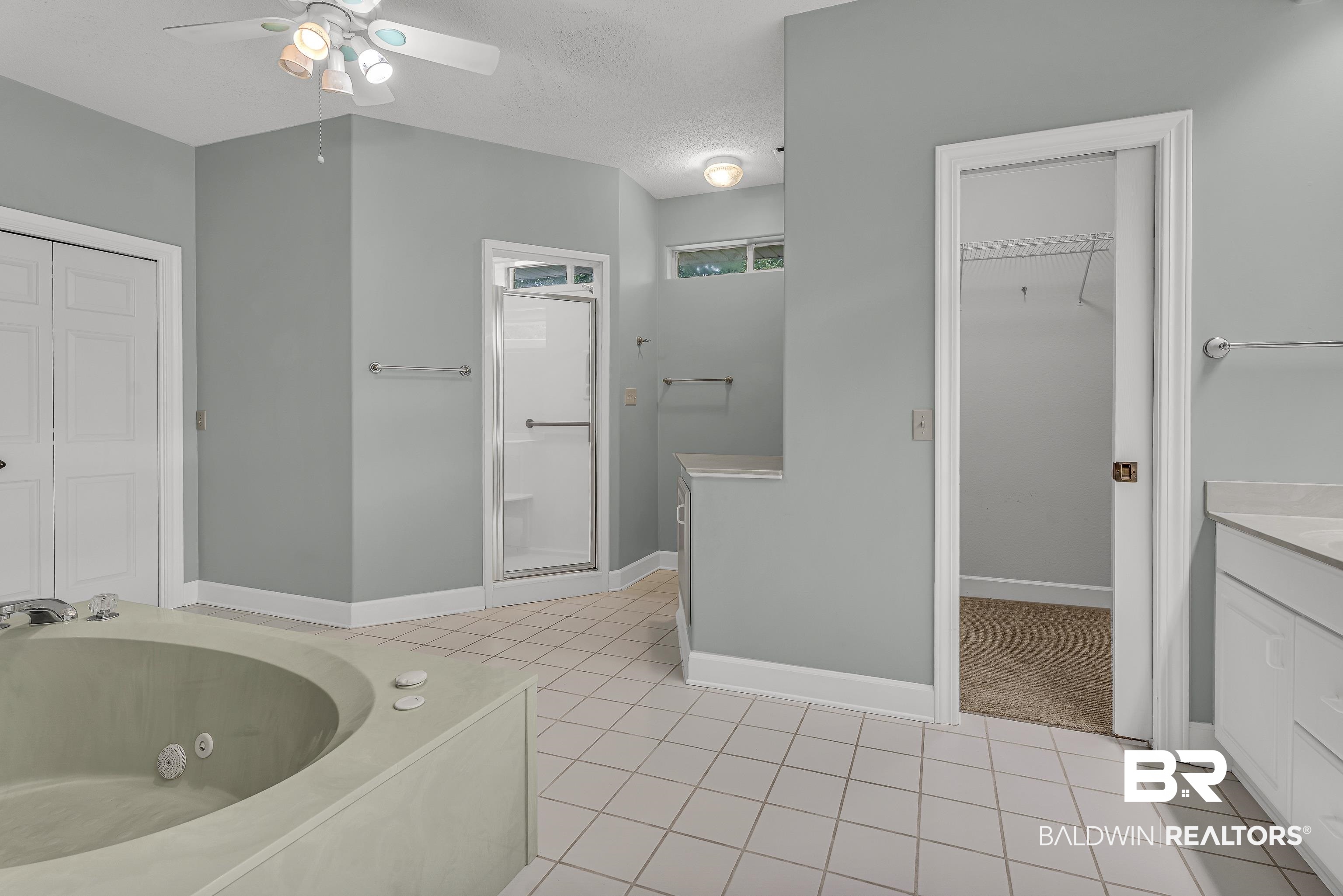 9530 Pilgrim Drive Elberta, AL 36530 - Photo 11 of 61 Bathroom with vanity, tile patterned flooring, a jetted tub, ceiling fan, and a textured ceiling