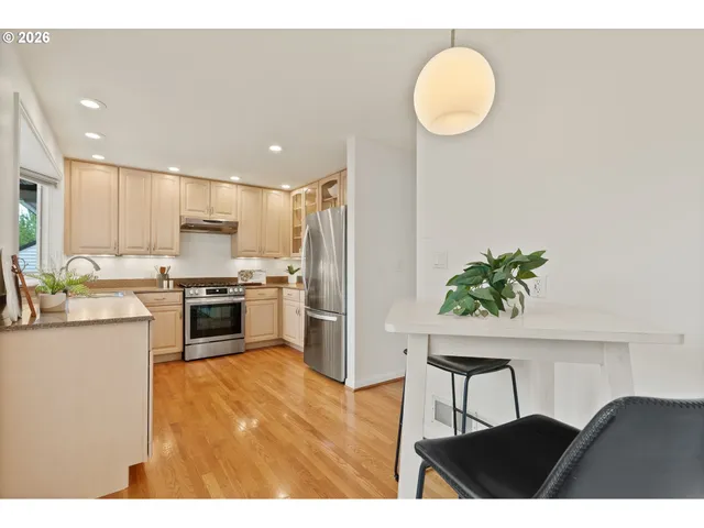 a kitchen with stainless steel appliances granite countertop a refrigerator a stove a sink dishwasher and white cabinets with wooden floor