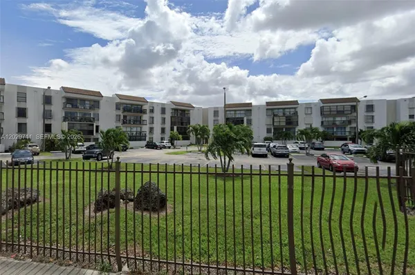 a view of a white building with a big yard and plants
