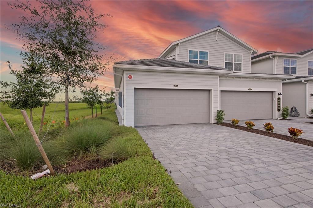 Traditional-style house with decorative driveway and a yard