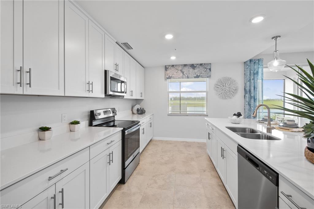 6008 Ellerston Way Avenue, Unit 1011 Immokalee, FL 34142 - Photo 14 of 50 Kitchen with appliances with stainless steel finishes, white cabinetry, pendant lighting, light stone countertops, and recessed lighting