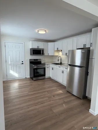 a kitchen with granite countertop a refrigerator and a stove top oven
