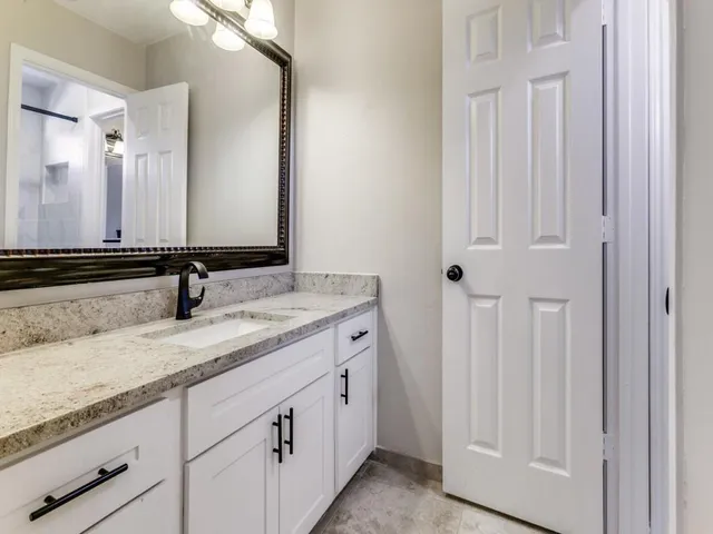 a bathroom with a granite countertop sink and a mirror