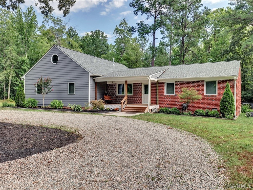 a view of a house with a yard plants and large tree