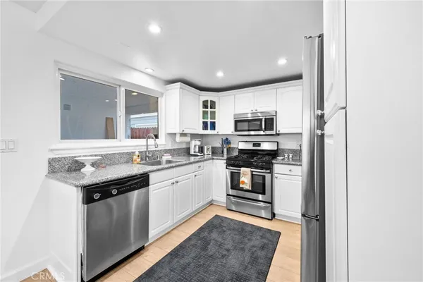 a kitchen with stainless steel appliances granite countertop a sink stove microwave and refrigerator