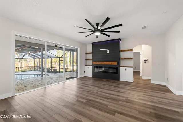 a view of an empty room with window and wooden floor