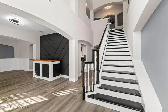 an empty room with wooden floor chandelier fan and windows
