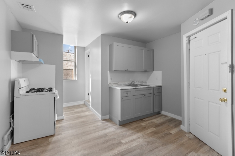 23 Monroe Street, Unit 2 Passaic, NJ 07055 - Photo 4 of 13 a kitchen with a refrigerator stove and white cabinets