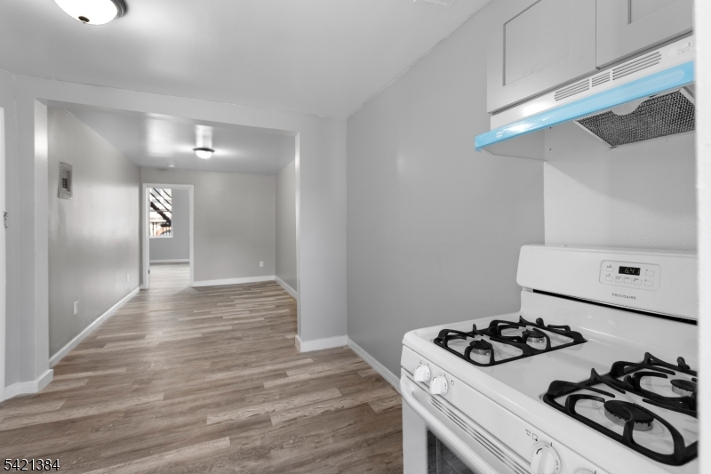 23 Monroe Street, Unit 2 Passaic, NJ 07055 - Photo 5 of 13 a view of a kitchen with a stove and wooden floor