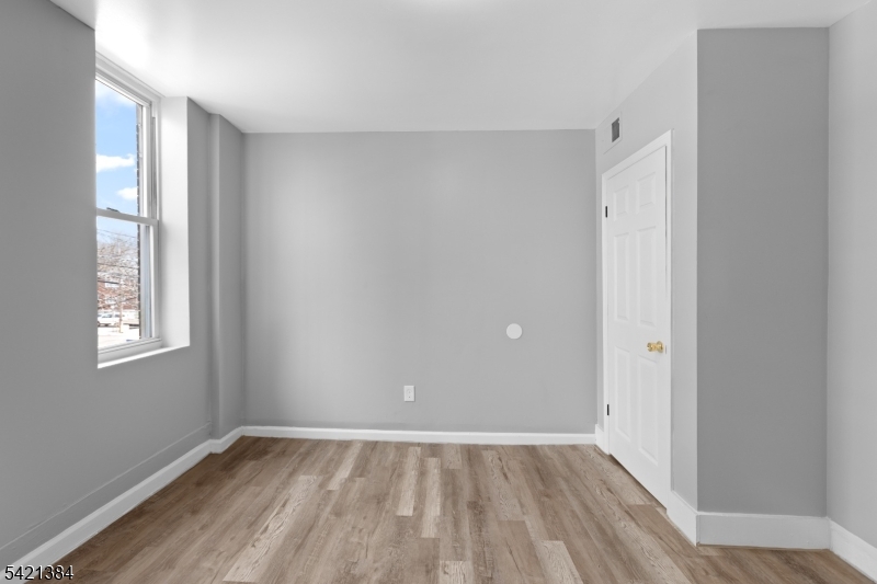 23 Monroe Street, Unit 2 Passaic, NJ 07055 - Photo 8 of 13 an empty room with wooden floor and windows