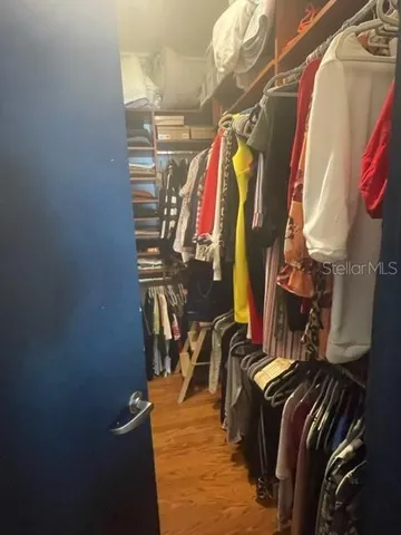 a view of walk in closet with clothes and shoes