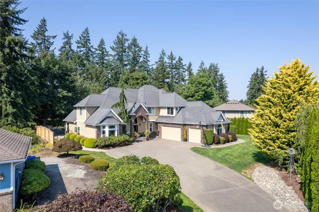 a view of a house with a big yard plants and large trees