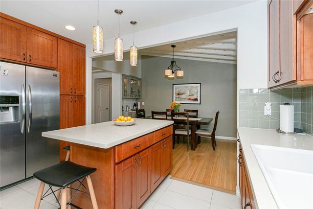 a kitchen with stainless steel appliances granite countertop a stove top oven a refrigerator a sink dishwasher a dining table and chairs with wooden floor