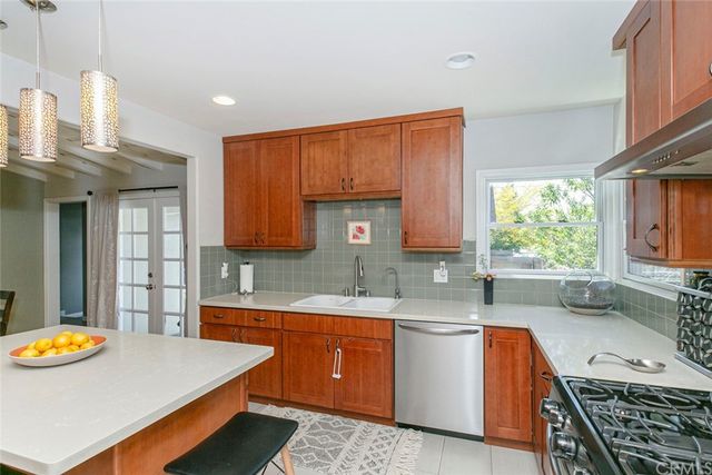 a kitchen with stainless steel appliances granite countertop a stove top oven a dining table and chairs with wooden floor