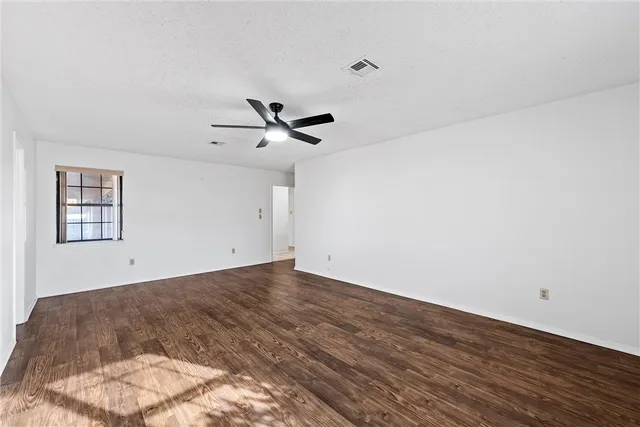 an empty room with windows and fan