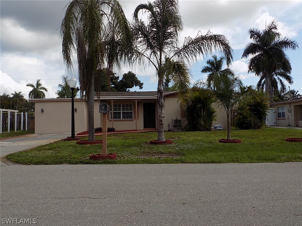 a view of a house with a yard and palm trees