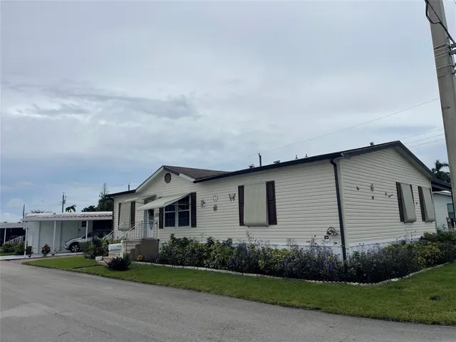 a view of a white house next to a yard and road