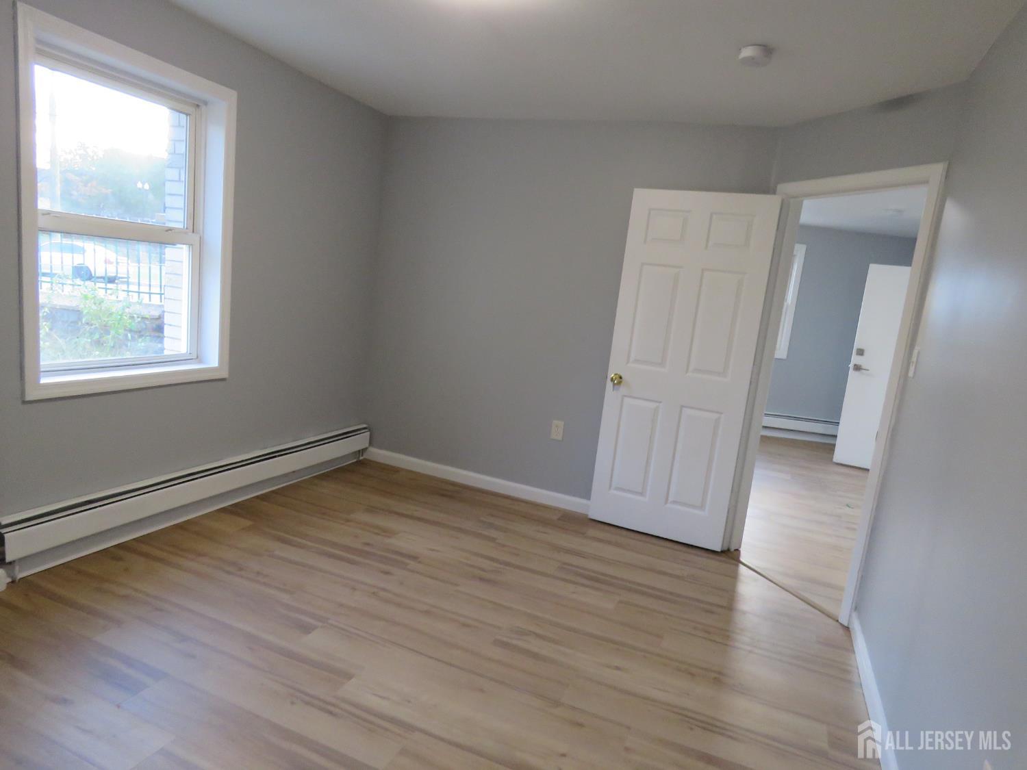 768 State Street Perth Amboy, NJ 08861 - Photo 9 of 35 an empty room with wooden floor and windows