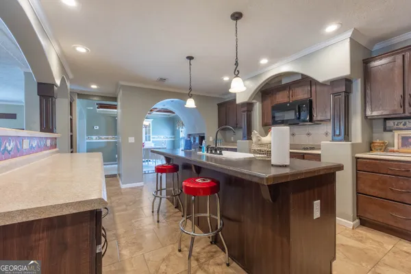 a kitchen with a stove a kitchen island a sink dining table and chairs