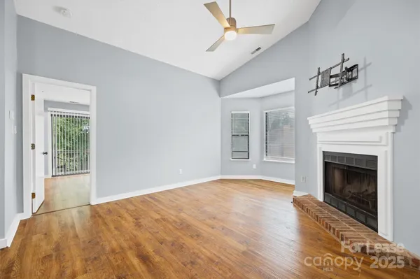 a view of empty room with a fireplace and wooden floor