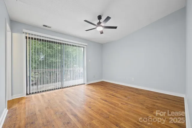 a view of empty room with wooden floor and ceiling fan