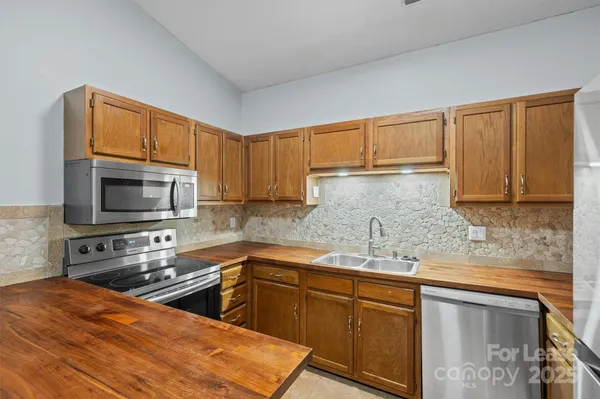 a kitchen with stainless steel appliances wooden cabinets a stove a sink and a microwave