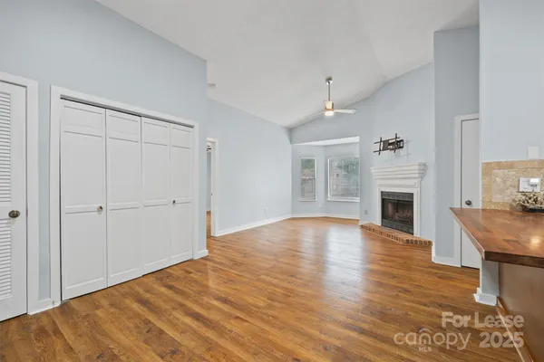 an empty room with wooden floor fireplace and windows