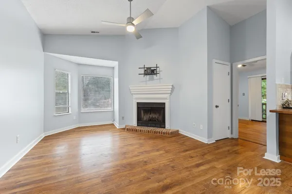 a view of empty room with wooden floor and fireplace