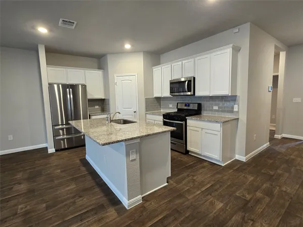 a kitchen with kitchen island a sink stove and refrigerator