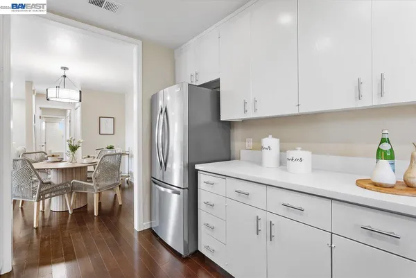 a kitchen with stainless steel appliances granite countertop a refrigerator a stove a dining table and chairs with wooden floor