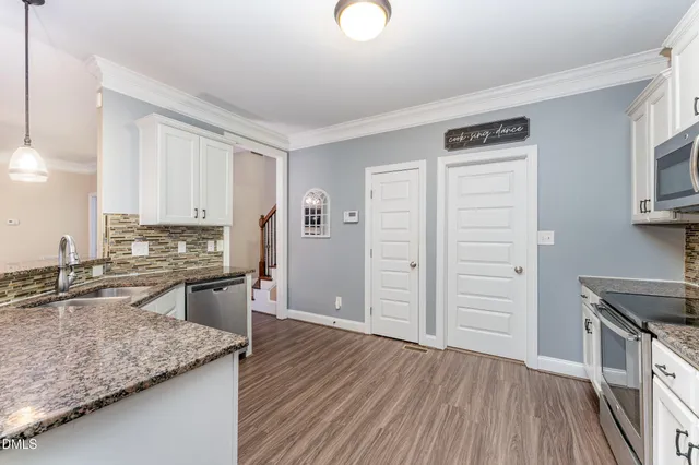 a kitchen with granite countertop white cabinets and stainless steel appliances
