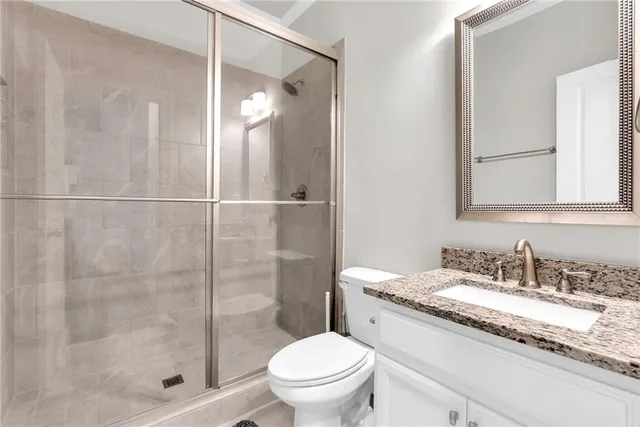 a bathroom with a granite countertop sink a toilet and shower