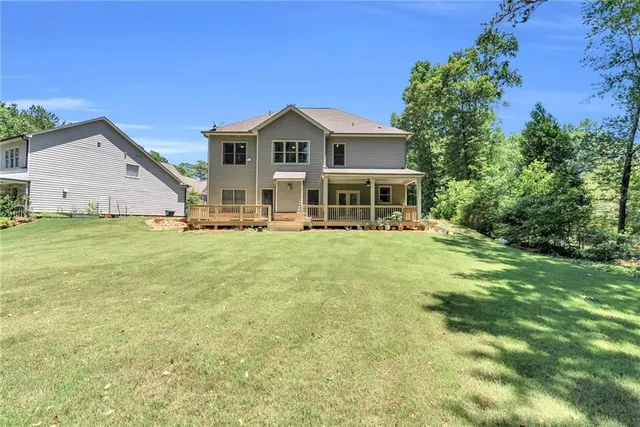 a big white house with a big yard and large trees with wooden fence